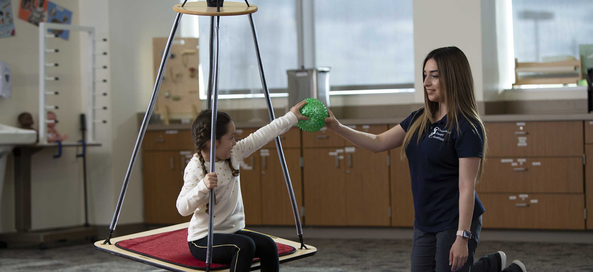 Occupational Therapy Assistant hands a ball to a child patient