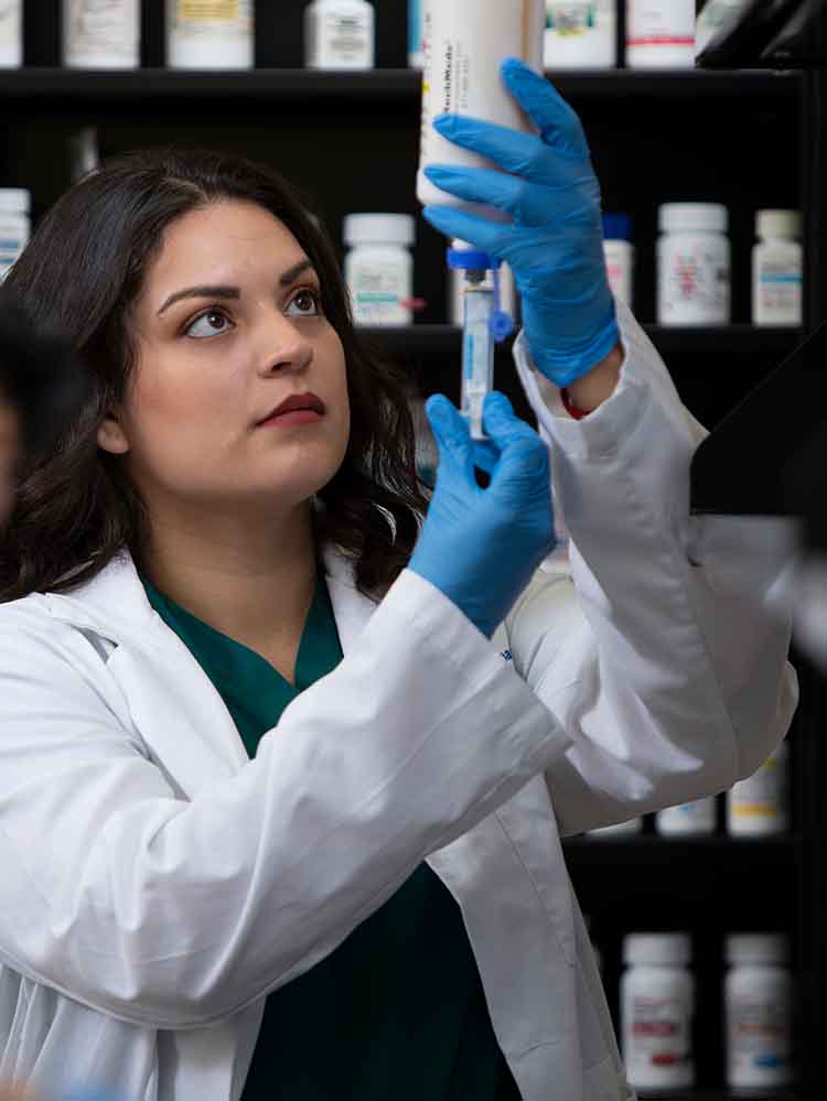 pharmacy tech measuring out amount of medicine needed in syringe